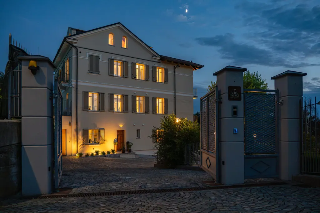 Villa Alba Palace illuminata al crepuscolo vista dal cancello d'ingresso